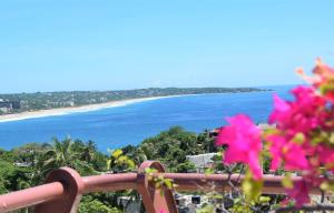 una vista sulla spiaggia da un balcone con fiori rosa di Hotel El Mirador a Puerto Escondido