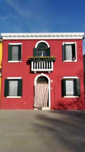 a red building with a door and a balcony at Casa degli Artisti in Burano