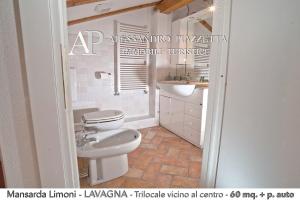 y baño con aseo blanco y lavamanos. en Mansarda Limoni, en Lavagna