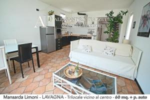 een woonkamer met een witte bank en een tafel bij Mansarda Limoni in Lavagna