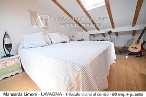 Cama blanca en habitación con guitarra en Mansarda Limoni, en Lavagna