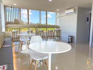 a white table and chairs in a room with windows at วัน บัดเจท เชียงราย สนามกีฬา One Budget Hotel Chiangrai Stadium in Chiang Rai
