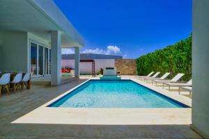 a swimming pool with lounge chairs and a house at GRAND Modern villa 6-Bedroom Brand New Heated Jacuzzi in Palm-Eagle Beach