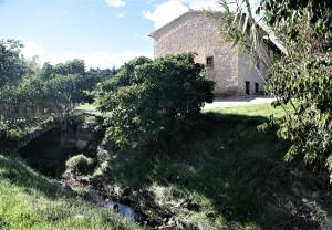 an old stone building next to a small river at Hort de L'Aubert in Cretas