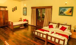 a bedroom with two beds with red pillows at Tea tours Ripon Heritage Bungalow in Meppādi