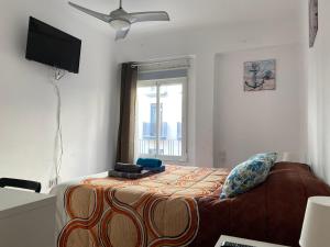 um quarto com uma cama, uma televisão e uma janela em Málaga Centro habitaciones privada en apartamento compartidos em Málaga