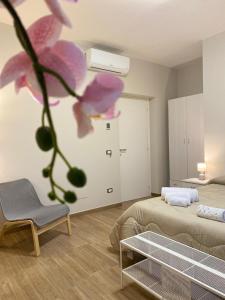 Pokój z 2 łóżkami, krzesłem i kwiatem w obiekcie B&B Ercole Agrigento w mieście Villaggio Mosè