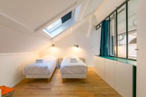 two beds in a room with a skylight at L'ATELIER DU CHAPEAU ROUGE EN PLEIN CENTRE VILLE in Dijon