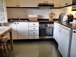 uma cozinha com armários brancos e um forno com placa de fogão em Villa Moreneta em Sobremazas