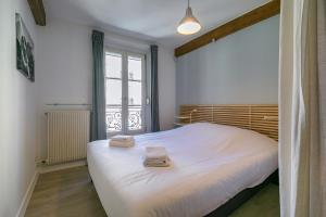 une chambre avec un grand lit blanc avec des serviettes dessus dans l'établissement LE ROUSSEAU charme et authenticité- SRloc, à Dijon