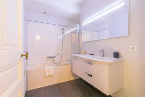 La salle de bains blanche est pourvue d'un lavabo et d'une douche. dans l'établissement Le Mucie*****LOFT au centre ville de Dijon, à Dijon