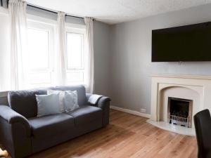 ein Wohnzimmer mit einem Sofa und einem Kamin in der Unterkunft Pass the Keys Cozy two bed flat near Glasgow Airport & Paisley in Paisley