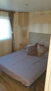 a large bed in a room with a window at Sylvie propriétaire du mobil-home " Camping de la Chanterie" in Saint-Pair-sur-Mer