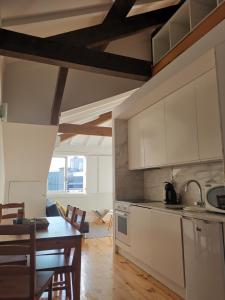 una cucina con mobili bianchi e un tavolo con sedie di YOUR PLACE PORTO I a Porto