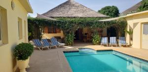 a swimming pool with chairs and a house at Villa Au Soleil in Saly Portudal