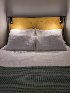 1 cama con almohadas blancas y cabecero de madera en Studio 7, Air-conditioned, 1 free parking, calm own entrance, en Jyväskylä