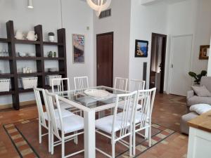 a dining room with a glass table and white chairs at GRAFEA Apartment Catania in Catania