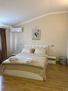 um quarto com uma cama grande com lençóis brancos e almofadas em Hotel 12 Tve em Mtskheta