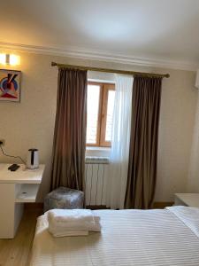 a bedroom with a bed and a desk and a window at Hotel 12 Tve in Mtskheta