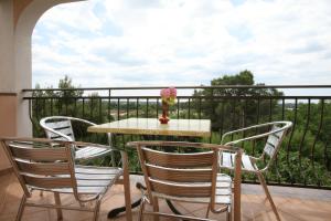 a table with three chairs and a vase of flowers on a balcony at Apartments Neda - Poreč South in Poreč