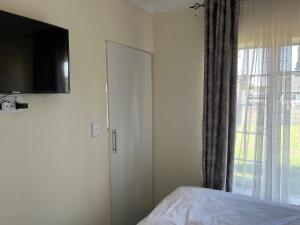 - une chambre avec un lit, une télévision et une fenêtre dans l'établissement House 210 holiday rentals, à Alberton