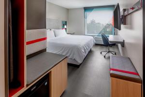 a hotel room with a bed and a desk and a window at avid hotels Milwaukee West - Waukesha by IHG in Pewaukee