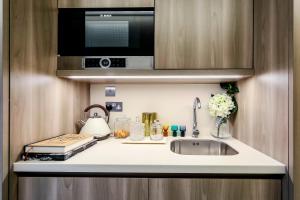 a kitchen counter with a sink and a microwave at The Quarters Swiss Cottage in London