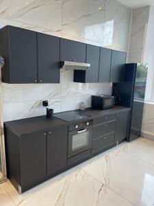 une cuisine avec des armoires noires et un four micro-ondes dans l'établissement Golden Suite - JACUZZI SAUNA, à Rouen