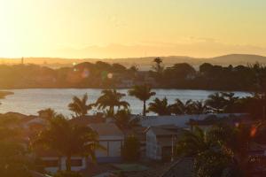 a sunset over a city with a body of water at Mirante de geriba! in Búzios