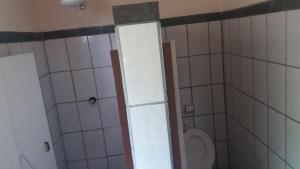 a small bathroom with a toilet and a shower at Recanto dos Carvalhos - Pousada Camping in São Lourenço