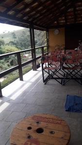 - une table et des chaises sur une terrasse couverte offrant une vue sur les montagnes dans l'établissement Recanto dos Carvalhos - Pousada Camping, à São Lourenço