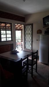 a kitchen with a table and a chair and a refrigerator at Recanto dos Carvalhos - Pousada Camping in São Lourenço