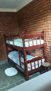two bunk beds in a room with a brick wall at Recanto dos Carvalhos - Pousada Camping in São Lourenço