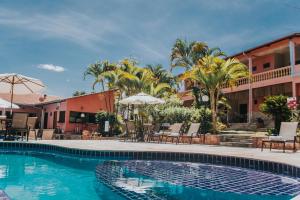 una piscina en un hotel con sillas y sombrillas en Pousada Villa Mariana, en Pirenópolis