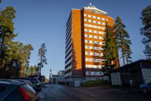a tall orange building with cars parked in a parking lot at Time Hostel NOVA - sairaalan vieressä in Jyväskylä