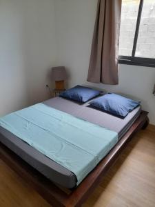 1 cama con almohadas azules en un dormitorio con ventana en Arum en Saint-Pierre