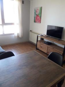 een woonkamer met een houten tafel en een televisie bij Departamento de Barrio Belgrano in Bariloche