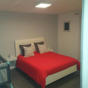 Un dormitorio con una cama roja con almohadas. en Agréable appartement, en Morbier