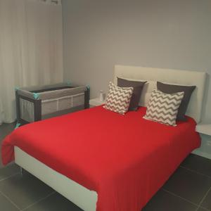 a bedroom with a red bed with pillows on it at Agréable appartement in Morbier