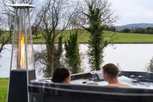 un homme et une femme dans une baignoire à côté d'un lac dans l'établissement Escape Ordinary at Lily's Pad, à Enniskillen