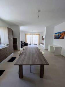 uma ampla sala de estar com uma mesa de madeira e cadeiras em Close to Airport apartment em Żejtun