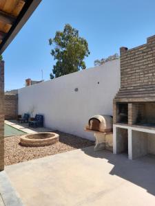 a patio with a pizza oven next to a white wall at Cabañas El Kincho in Albardón