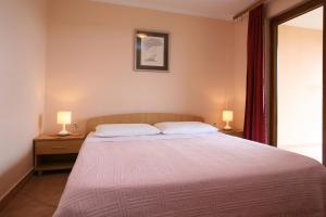 a bedroom with a large bed with two lamps at Apartments Neda - Poreč South in Poreč