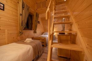 a bedroom with two beds and a staircase in a log cabin at Kozie Ranczo Domek Bacy in Bańska Niżna