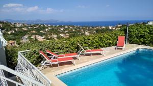 a swimming pool with chairs and a view of the ocean at Les Myrtes in Les Issambres