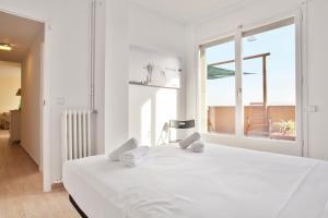 a white bedroom with a large bed and a window at Stay U-nique Apartments Marina III in Barcelona