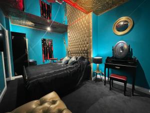 a bedroom with blue walls and a bed and a desk at Boutique Dungeon in Brighton & Hove