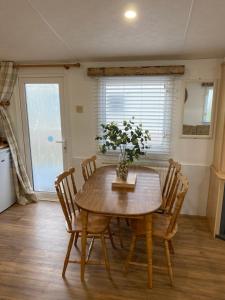 a dining room table with chairs and a vase with a plant at Great Deals at The Grange, Ingoldmells in Skegness