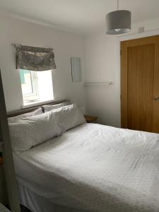 a white bed in a bedroom with a window at Ty Bach in Bagillt