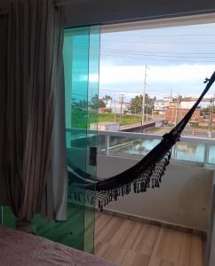 a hammock in a room with a large window at Studio A completo 400m da praia in Porto De Galinhas